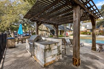 A wooden pergola is over a hot tub in a backyard.